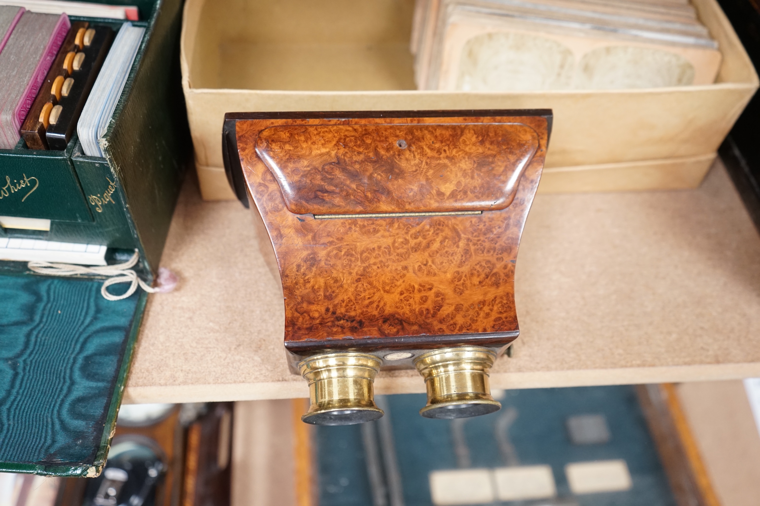 A Cook's patent stereoscope viewer and viewing cards together with a green Morocco leather playing cards box, box 12.5cm high x 24cm wide. Condition, games box poor, viewer and cards good